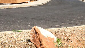 A desert-style building with a paved driveway and a mountain view in the background. - Desert Willow Rim Vista 6A7 (Moab)