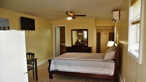 A bedroom with a bed, a desk, a chair, a ceiling fan, a mirror, and a window with blinds. - Private One Bedroom Cottage- Bonefish Creek (Barretarre)