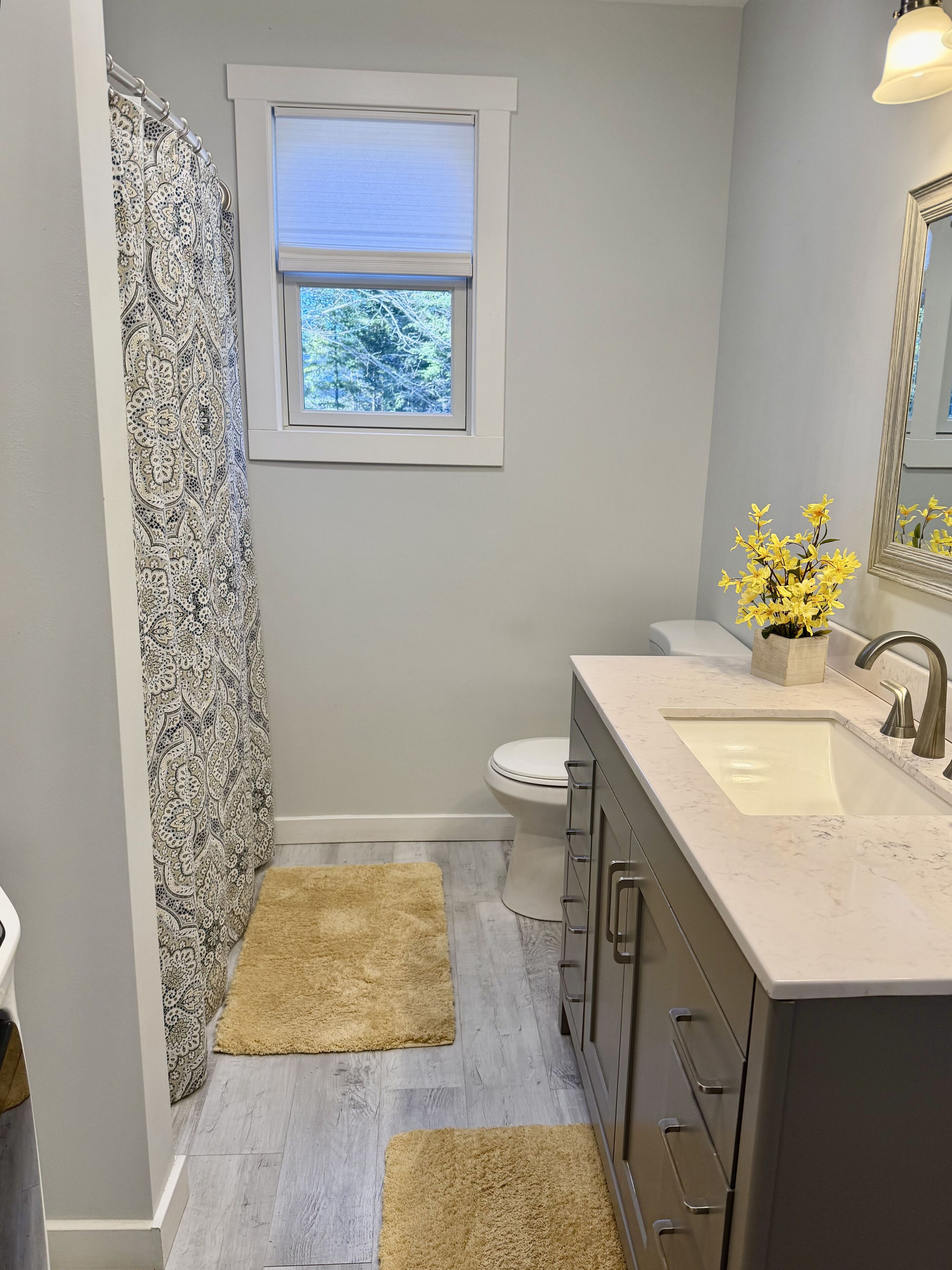 A bathroom with a toilet, sink, and window.