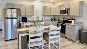 A modern kitchen with stainless steel appliances, a granite countertop, and light-colored cabinetry. - Waterfront Cottage on Private Island near Acadia (Milbridge)