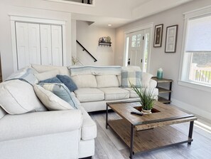 A living room with a sofa, coffee table, and a staircase.
