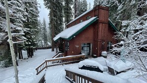 A rustic cabin with a green roof, surrounded by snow-covered trees. - Quiet & Large house - Hot Tub, Pool table, Fast WiFi  -  close to Kings Beach! (Tahoe Vista)