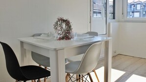 A dining area with a white table, two chairs, and a vase of flowers. - Espacioso apartamento - El Nido de Ris 6918 (Noja)