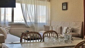 A cozy living room with a sofa, a dining table with chairs, and a window with sheer curtains. - Espacioso apartamento - El Nido de Ris 6918 (Noja)