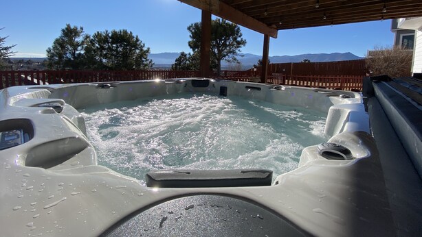 Un jacuzzi bajo una pérgola de madera con vistas a la montaña.