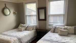 A bedroom with two beds, a clock, and a mirror on the wall. - The Apollo (Charleston)