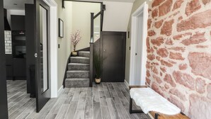A modern interior with a staircase, a bench, and a stone wall. - Ty Coch (Ruthin)