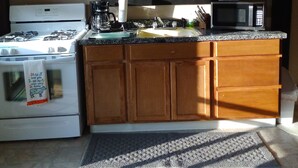 A compact kitchen with wooden cabinets, a stove, a microwave, and a window with blinds. - Reduced to 110.00 March-July  week nites (Weedville)