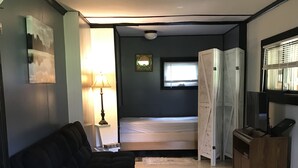 A compact living space with a sofa, a small table, a bed, and a wooden cabinet. - Reduced to 110.00 March-July  week nites (Weedville)