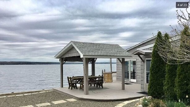 A covered outdoor seating area with a table and benches, overlooking a body of water. - Live your Best Vacation Life! Lovely 4 BR Property on Cayuga Lake.  Dog Friendly (Aurora)