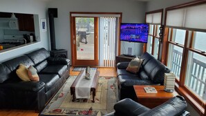 A living room with a black leather sofa, a wooden coffee table, and a television on a stand. - Live your Best Vacation Life! Lovely 4 BR Property on Cayuga Lake.  Dog Friendly (Aurora)
