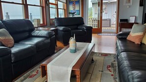 A living room with two black leather sofas, a wooden coffee table, and a patterned rug. - Live your Best Vacation Life! Lovely 4 BR Property on Cayuga Lake.  Dog Friendly (Aurora)