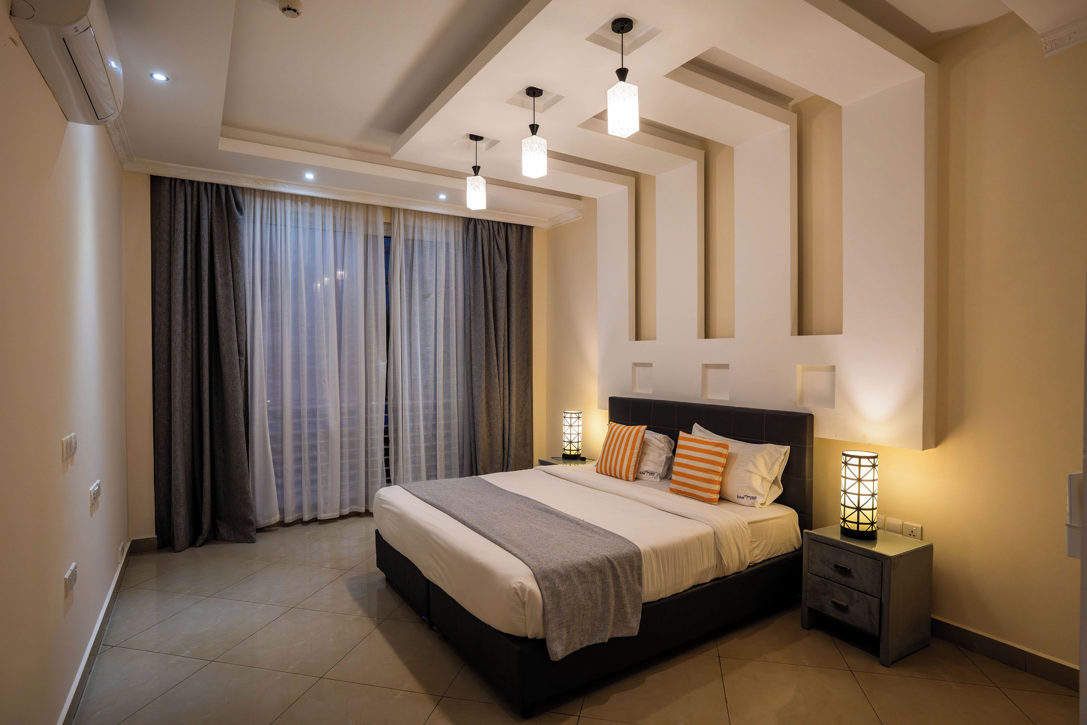 Un dormitorio moderno con una cama grande, lámparas de noche y un candelabro en el techo.
