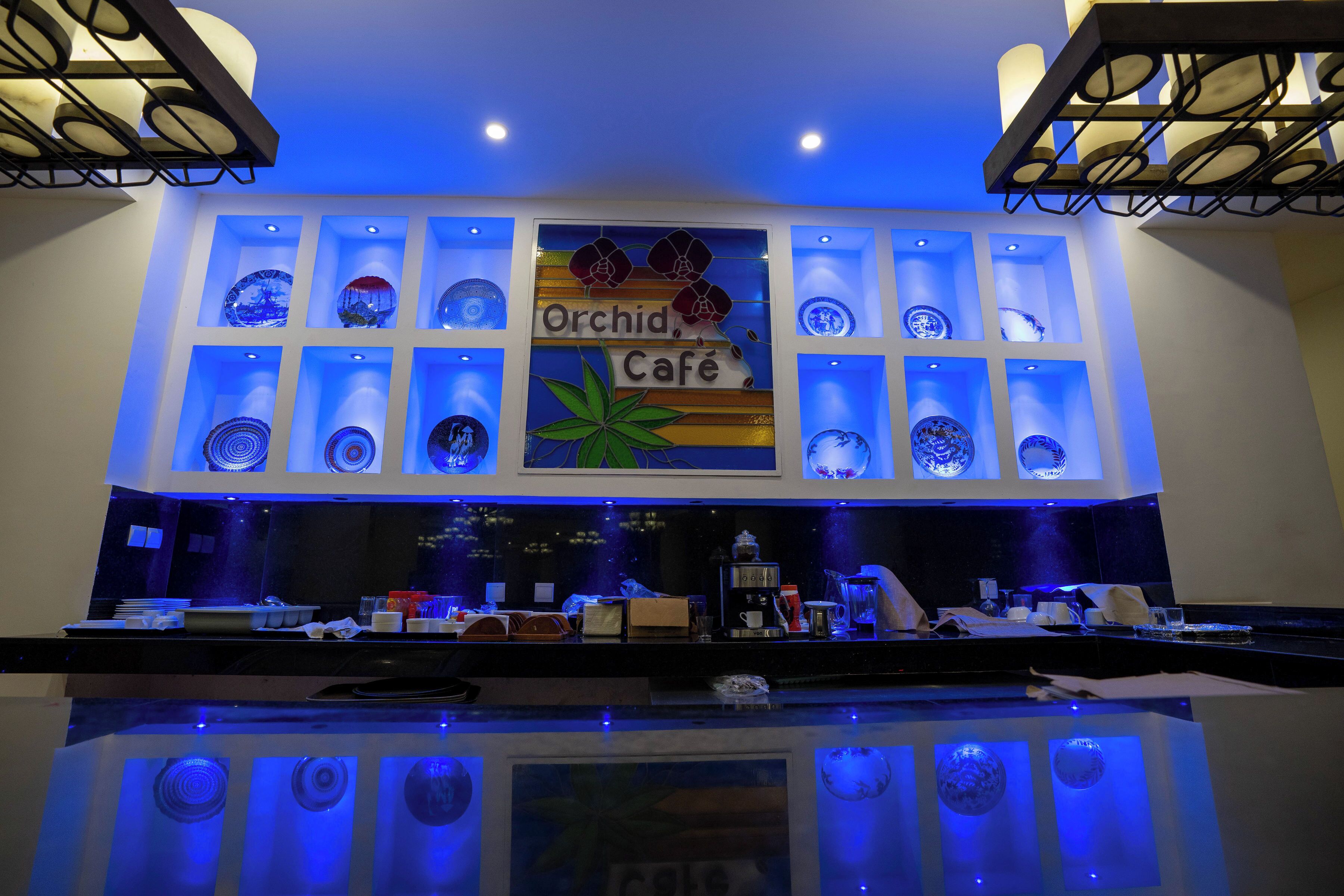 Un café con un letrero que dice "Orchid Café" y estantes mostrando platos de cerámica azules y blancos.