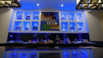 Un café con un letrero que dice "Orchid Café" y estantes mostrando platos de cerámica azules y blancos.