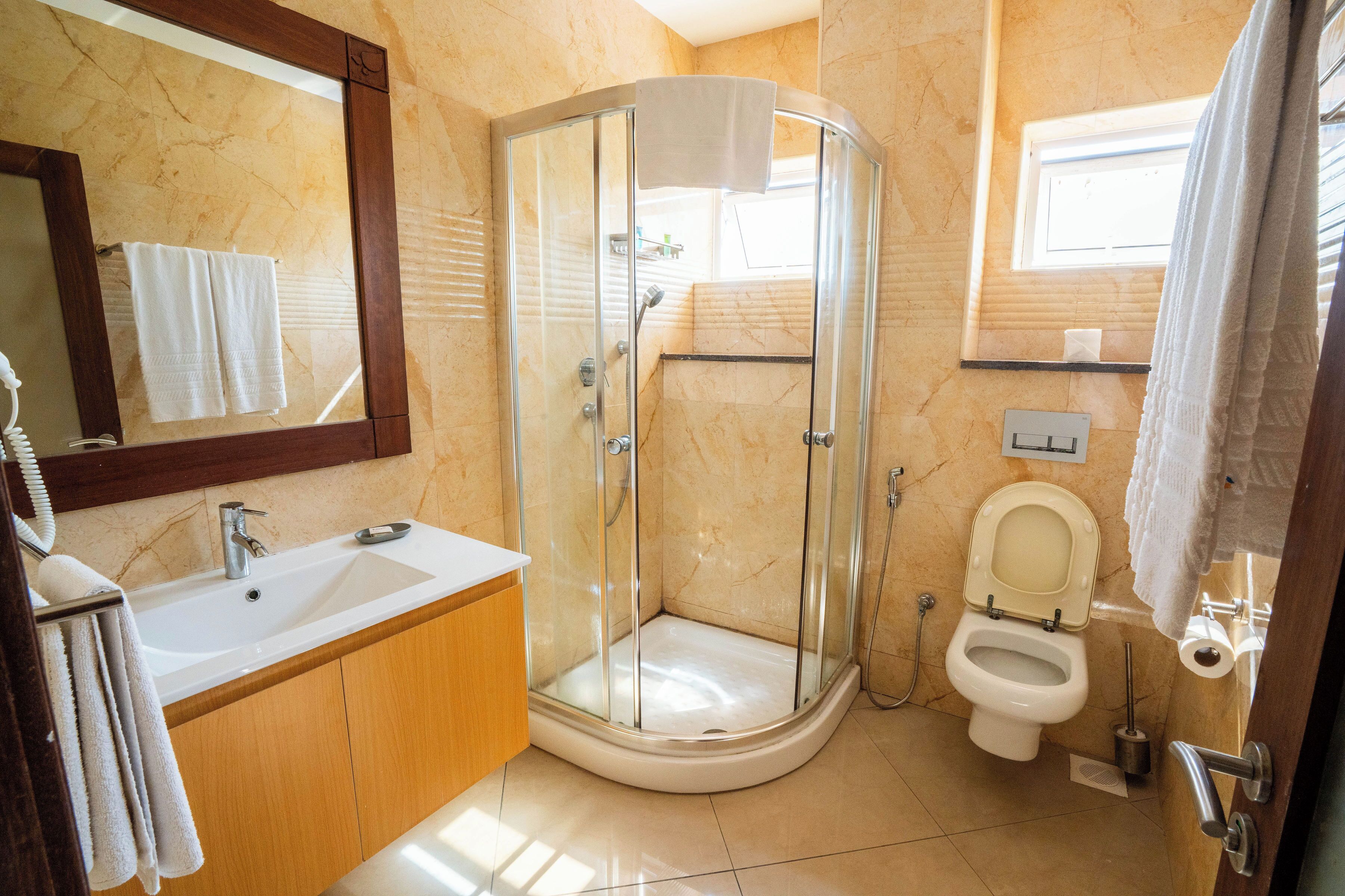 A bathroom with a glass-enclosed shower, a sink, a toilet, and a mirror.