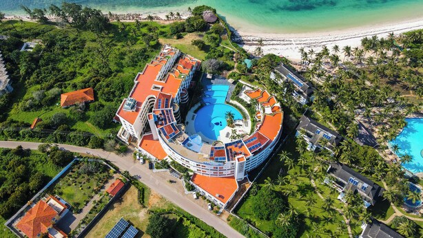 An aerial view of a resort with a central swimming pool, multiple buildings, and a beach. - Kilua Residences by CityBlue, Mombasa (Mombasa)