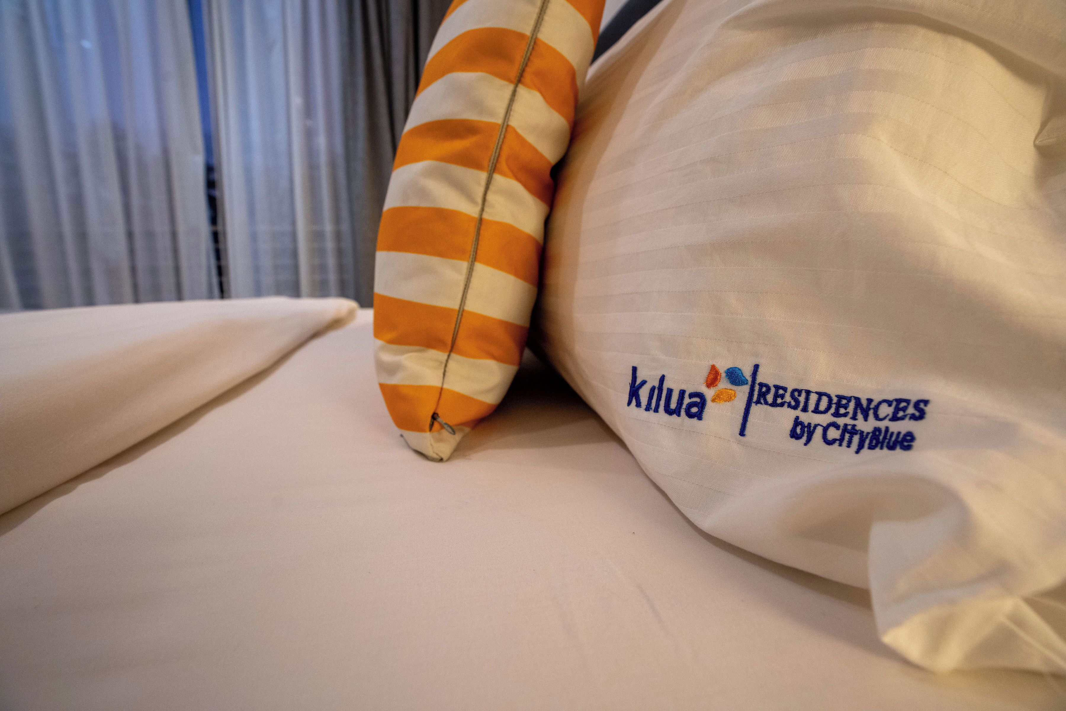 Ein Kissen mit Streifenmuster und ein Kissen mit Logo und Schriftzug.