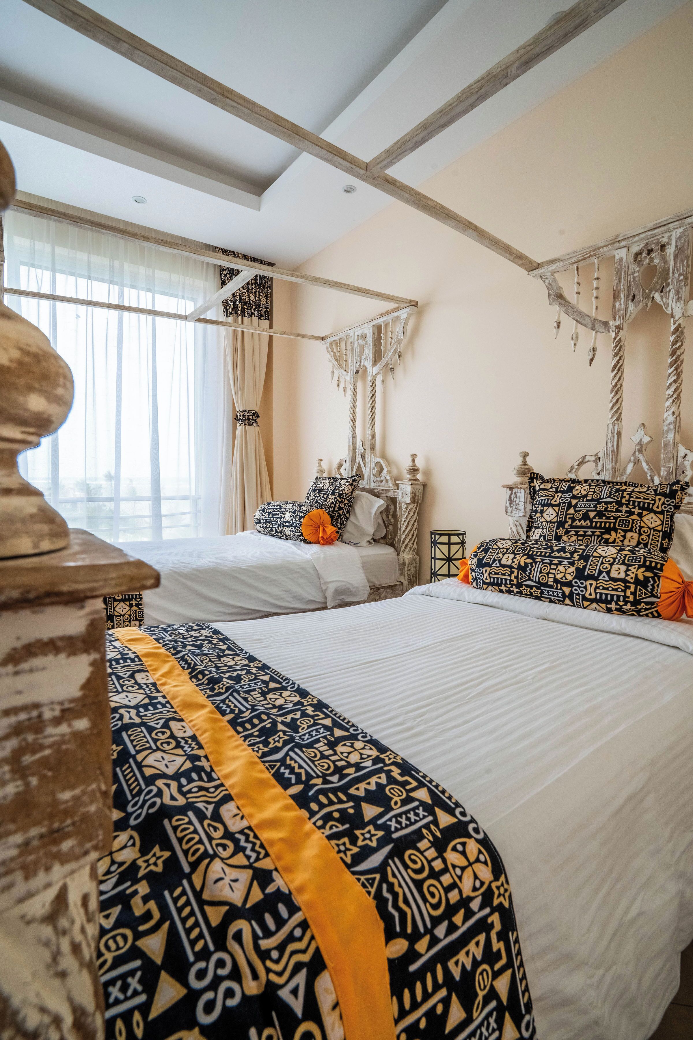 A bedroom with a large bed, a smaller bed, and a decorative headboard.