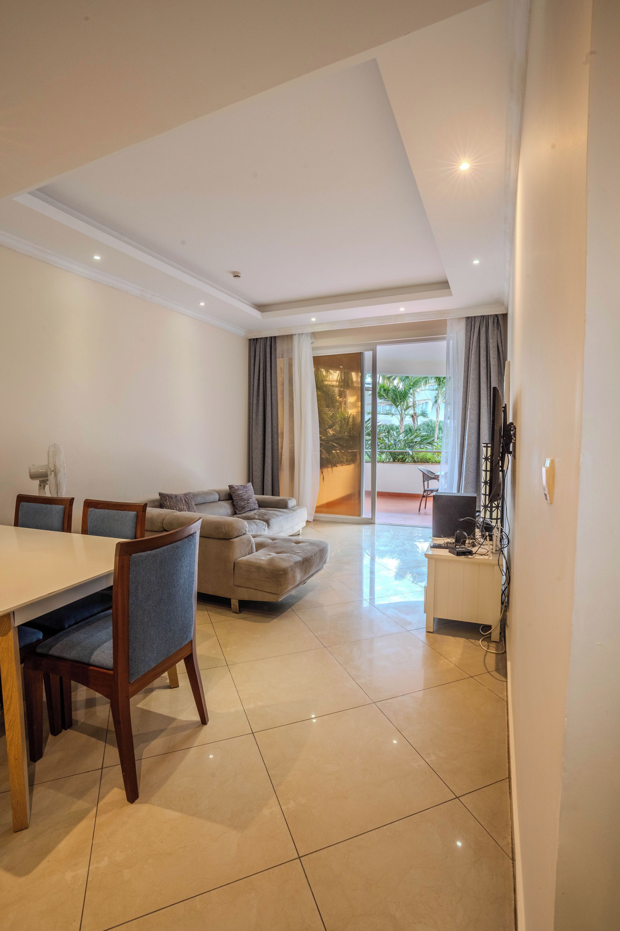A modern living room with a dining area, a sofa, and a TV.