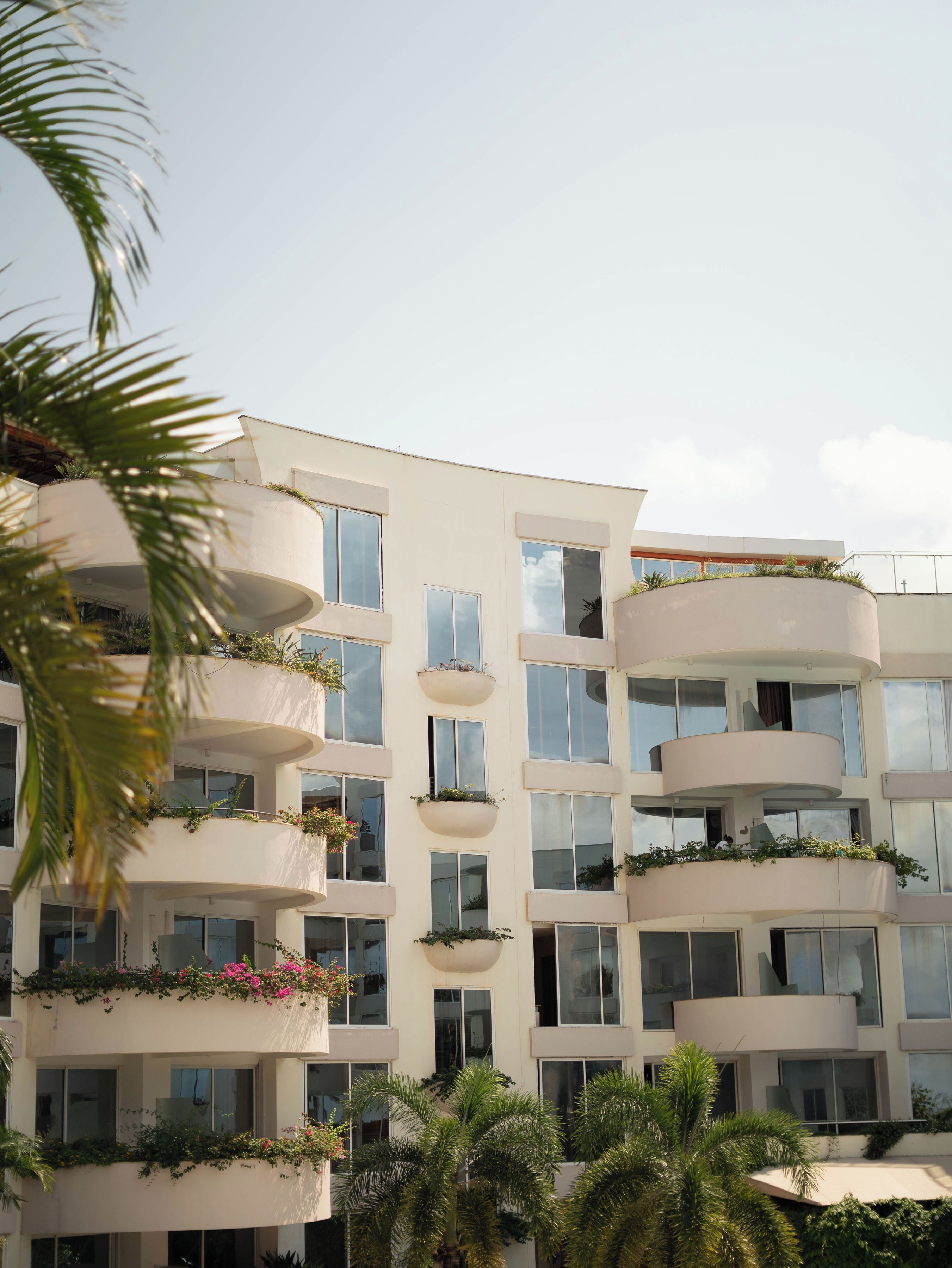 Un immeuble à plusieurs étages doté de balcons, chacun orné de plantes et de fleurs.