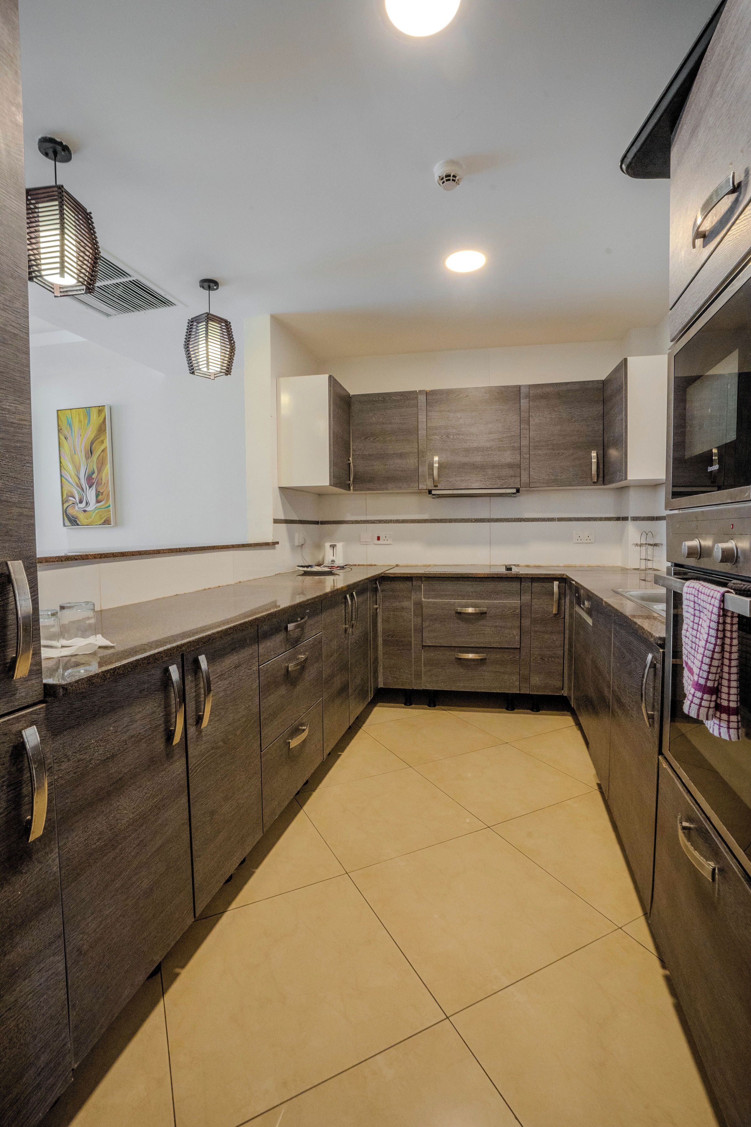 A modern kitchen with dark wood cabinets, stainless steel appliances, and a tiled floor.