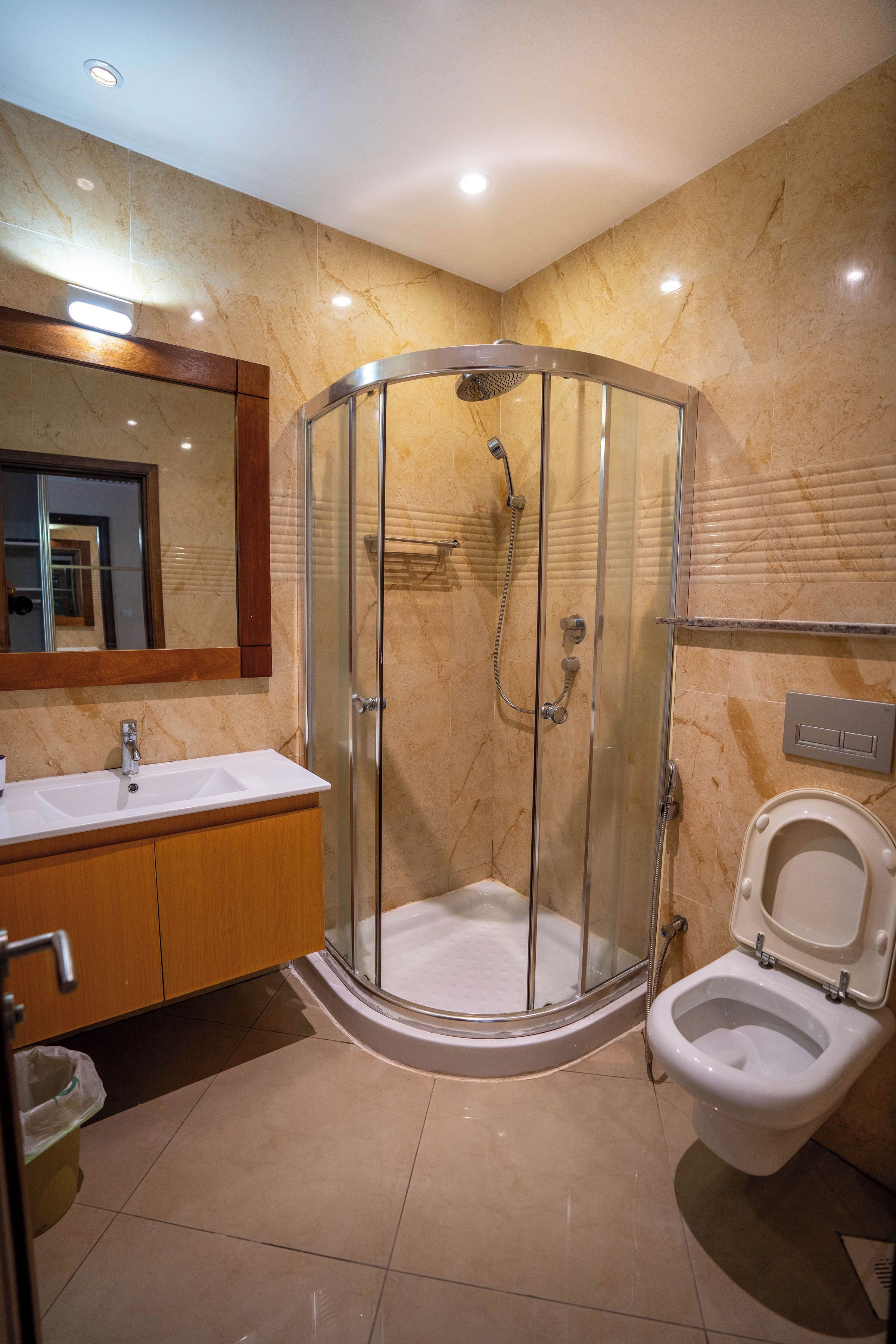 A modern bathroom with a glass-enclosed shower, a white sink, and a toilet.