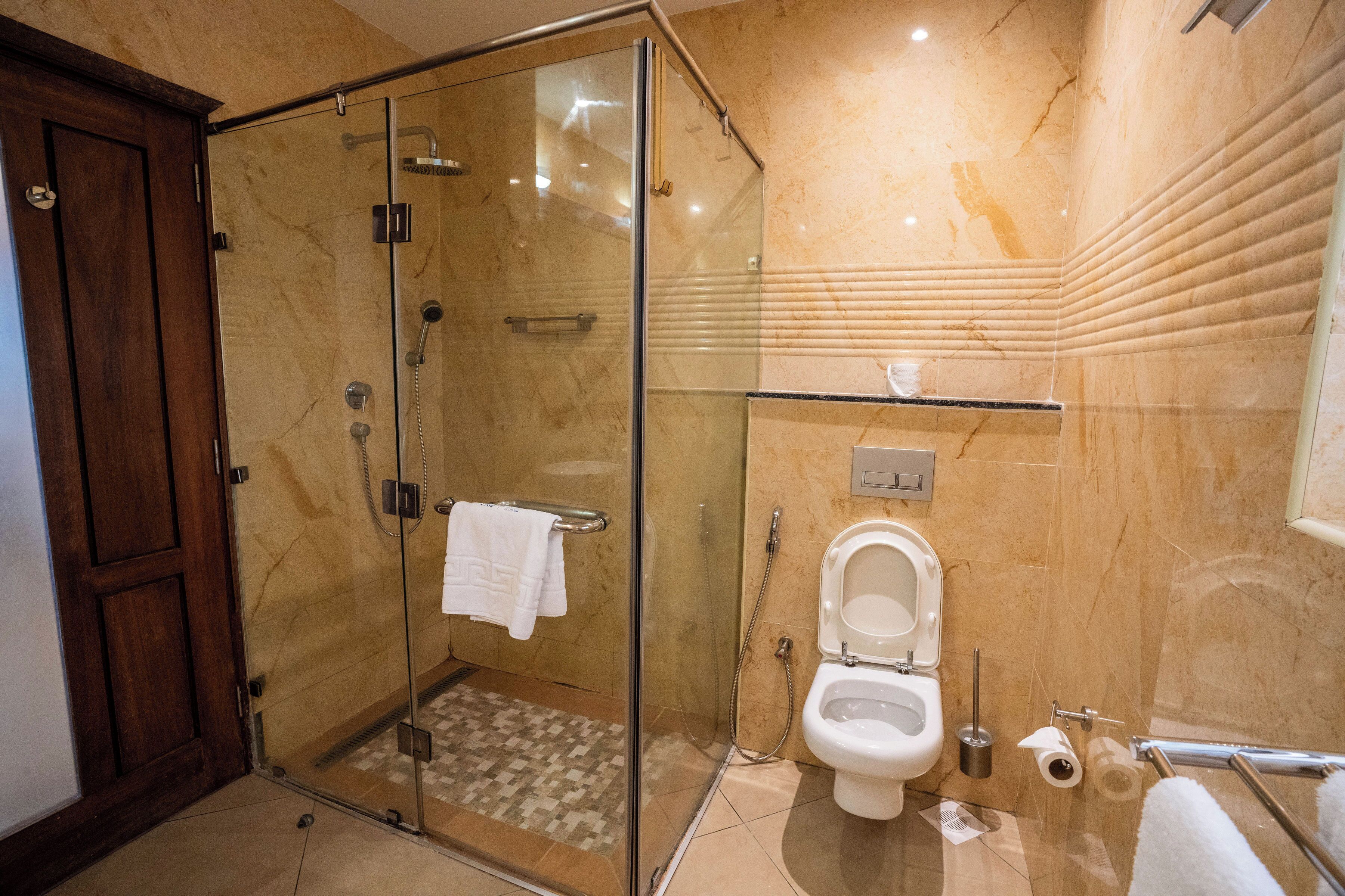 A modern bathroom with a glass-enclosed shower, a toilet, and a sink.