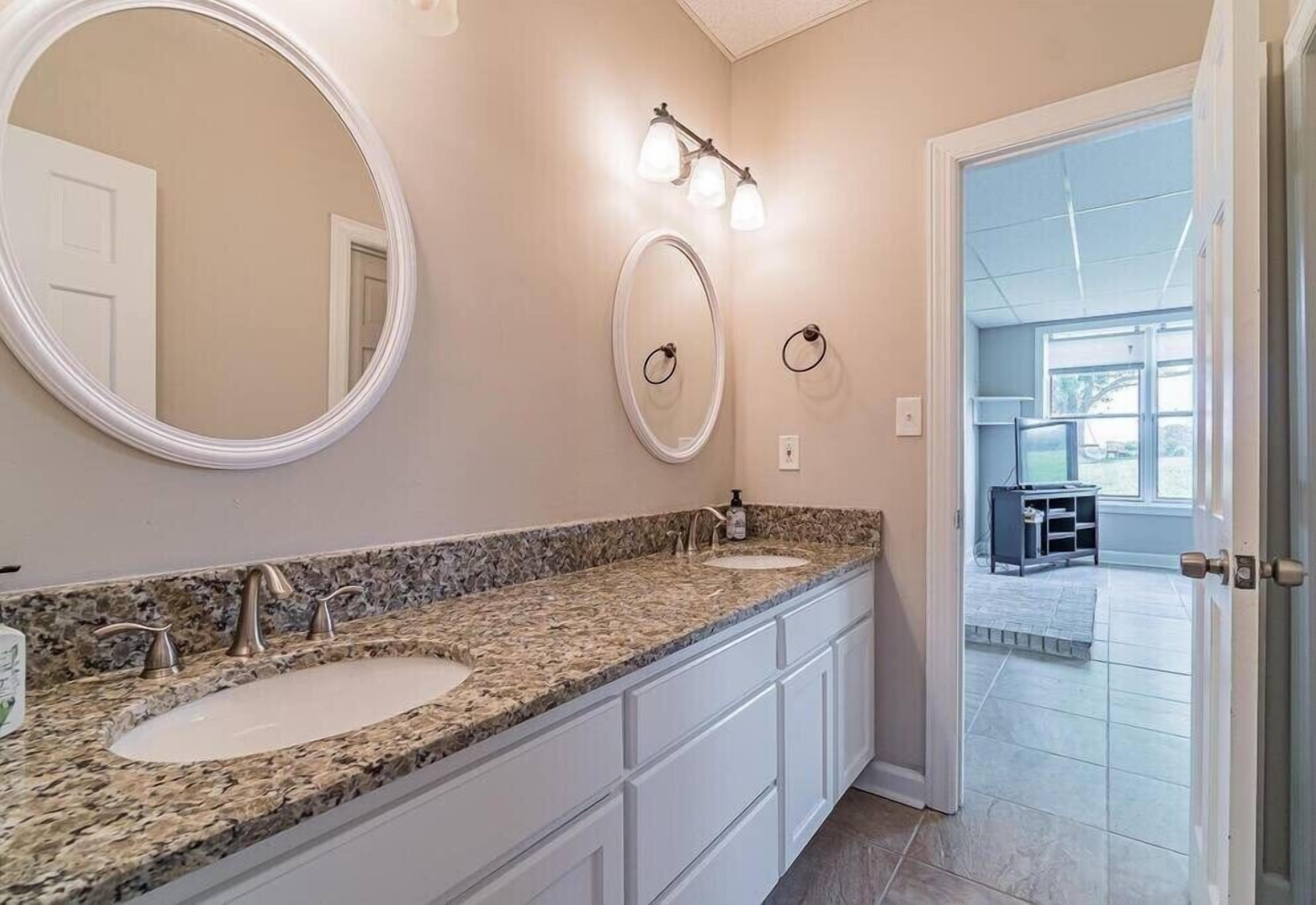 A bathroom with two sinks, a large mirror, and a vanity with cabinets.