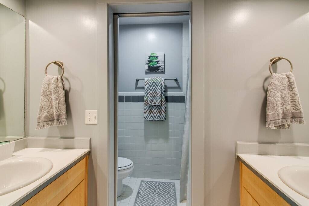 A bathroom with two sinks, a toilet, and a shower.