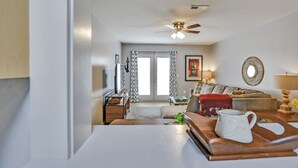Un salon moderne avec un ventilateur de plafond, un canapé, une table basse et un téléviseur.