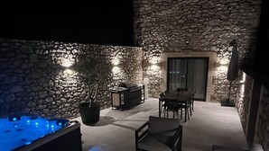Eine Terrasse mit Steinwänden, einem Whirlpool, Sitzgelegenheiten und einem Essbereich.