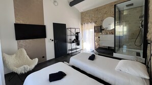 Ein modernes Hotelzimmer mit zwei Betten, einer Dusche, einem Fernseher und einer Steinwand.