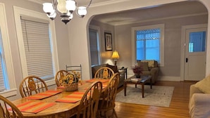 A dining area with a wooden table and chairs, a chandelier, and a lamp. - Twin Porch Retreat (Cambridge)