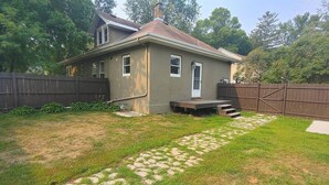 A single-story house with a front porch, a small deck, and a fenced backyard. - Twin Porch Retreat (Cambridge)