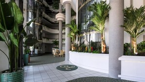 A spacious indoor atrium with high ceilings, large windows, and a variety of indoor plants. - Ashley Collection (Daytona Beach Shores)