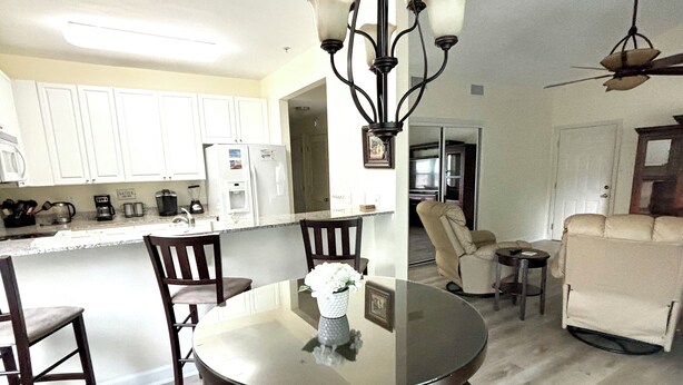 A dining area with a round table, four chairs, and a chandelier.
