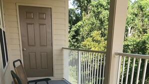 A covered porch with two wicker chairs and a door.