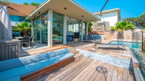 Um pátio moderno ao ar livre com piscina, deck de madeira e áreas de estar.