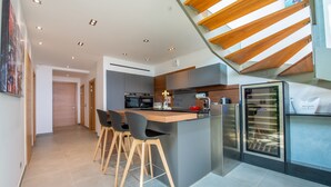 Cozinha moderna com ilha central, banquetas e forno embutido.
