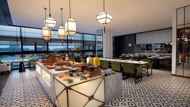 A modern dining area with geometric patterned flooring, a central buffet table, and pendant lighting. - Ramada Plaza by Wyndham Xiangtan Wanlou (Xiangtan)