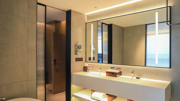 A modern bathroom with a large mirror, a white sink, and a bathtub. - Novotel Dongguan Songshan (Dongguan)