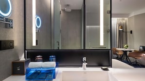 A modern bathroom with a large mirror, a white sink, and a blue storage unit.
