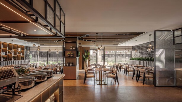 A modern restaurant with a high ceiling, exposed beams, and a mix of seating arrangements. - Novotel Dongguan Songshan (Dongguan)