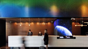 A hotel reception area with a large digital screen displaying a space-themed image, a reception desk, and a check-in counter. - Novotel Dongguan Songshan (Dongguan)