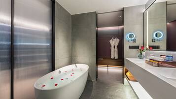 A modern bathroom with a freestanding bathtub, a vanity with a mirror, and a shower area.