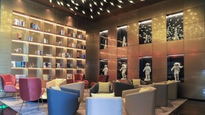 A modern lobby with a large bookshelf, comfortable seating, and decorative statues. - Novotel Dongguan Songshan (Dongguan)