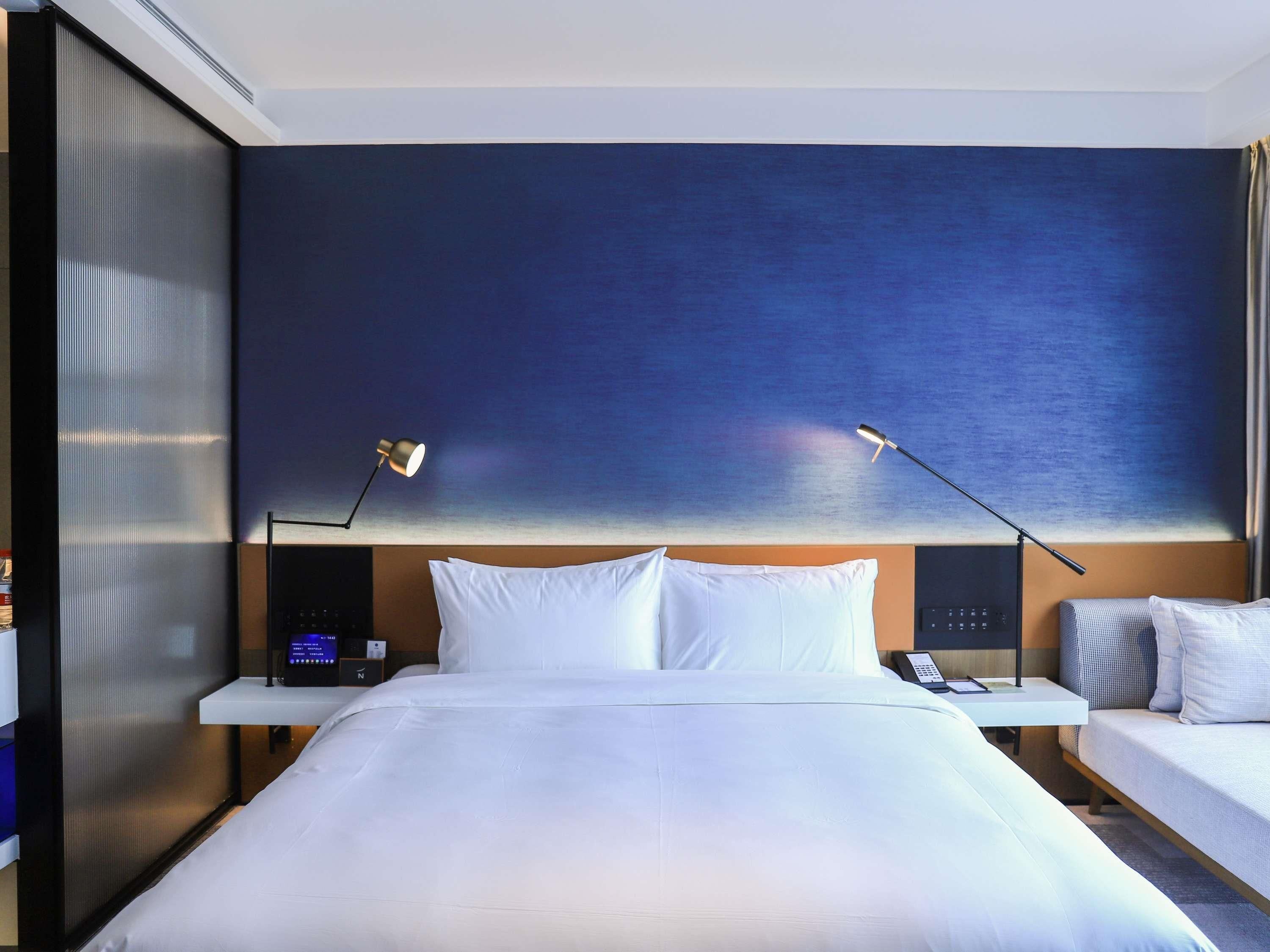 A hotel room with a large bed, two bedside tables, a desk, and a chair.