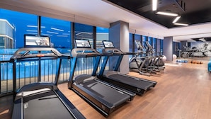 A gym with treadmills, exercise bikes, and a large window overlooking a body of water.