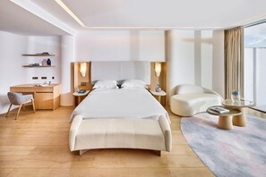 Camera d'albergo moderna con un letto grande, una scrivania, una sedia, un divano e un tavolino con piano in vetro.